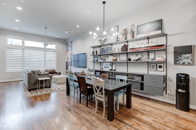 dining space with light hardwood / wood-style floors and a notable chandelier