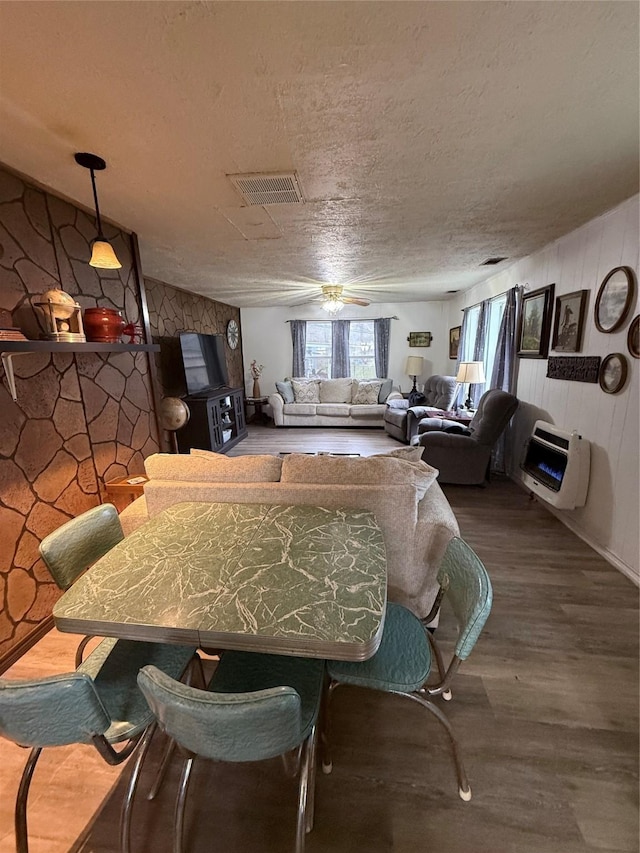 dining space featuring a textured ceiling, heating unit, hardwood / wood-style flooring, and ceiling fan