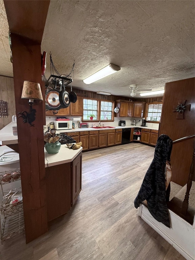 kitchen featuring wood walls, sink, ceiling fan, light wood-type flooring, and kitchen peninsula