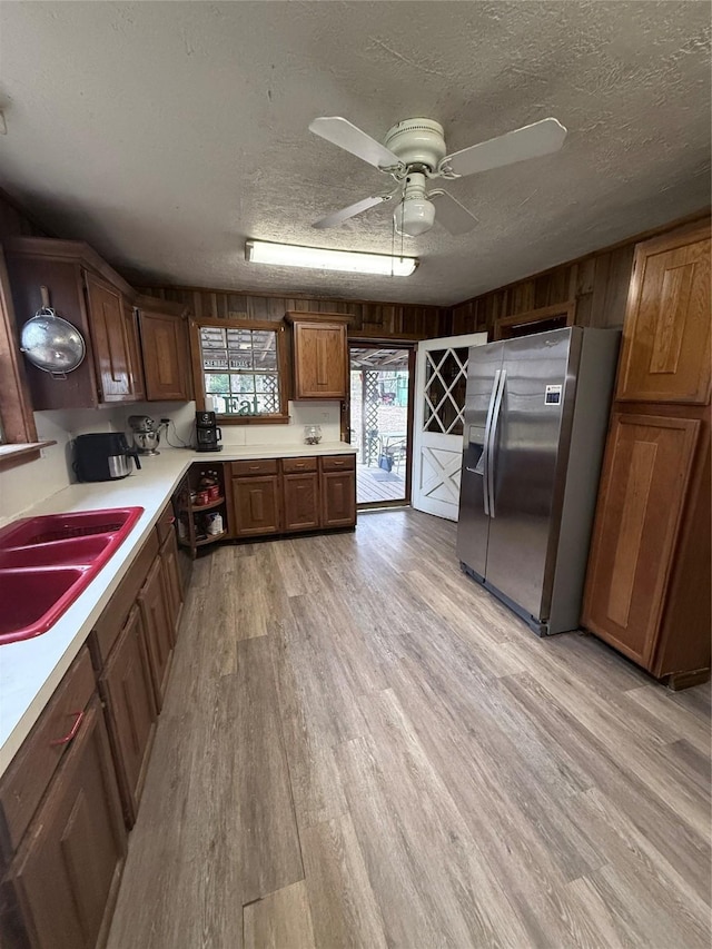 kitchen with ceiling fan, sink, stainless steel fridge, light hardwood / wood-style floors, and a textured ceiling