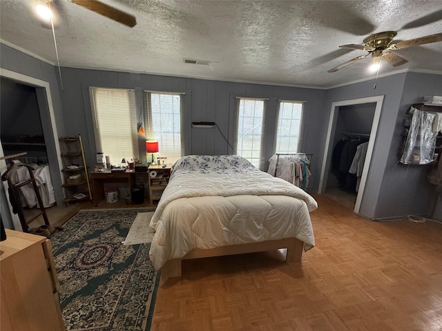 bedroom featuring ceiling fan, parquet flooring, a textured ceiling, and a closet