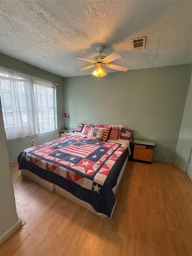 bedroom featuring ceiling fan, a textured ceiling, and light wood-type flooring