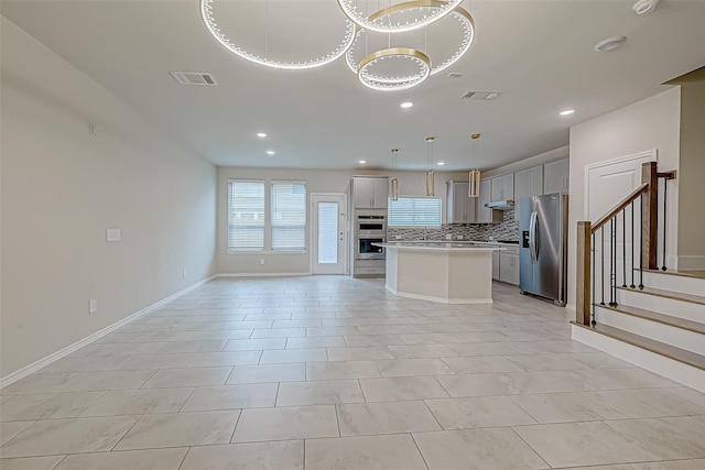 kitchen featuring pendant lighting, light tile patterned floors, tasteful backsplash, a kitchen island, and stainless steel appliances