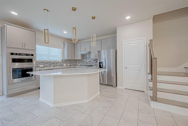 kitchen with gray cabinets, tasteful backsplash, decorative light fixtures, a kitchen island, and stainless steel appliances