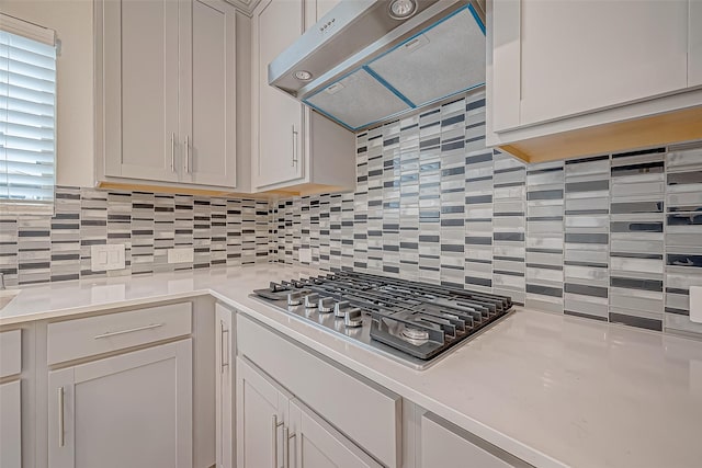 kitchen with tasteful backsplash, ventilation hood, white cabinetry, and stainless steel gas cooktop