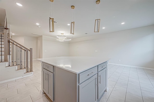 kitchen with a center island, hanging light fixtures, gray cabinetry, and light tile patterned flooring