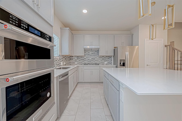 kitchen featuring backsplash, sink, hanging light fixtures, appliances with stainless steel finishes, and white cabinetry