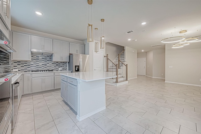 kitchen featuring tasteful backsplash, gray cabinetry, stainless steel appliances, pendant lighting, and a center island