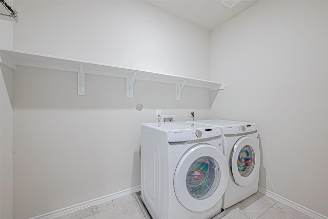 laundry area featuring light tile patterned floors and washing machine and dryer