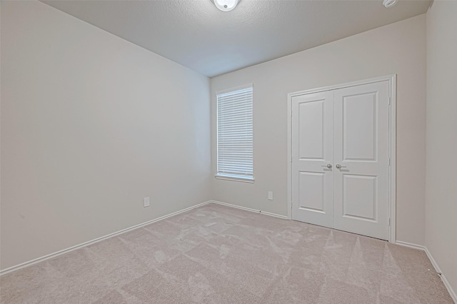 unfurnished bedroom featuring a textured ceiling, light carpet, and a closet