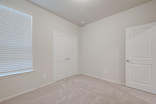 unfurnished bedroom with light carpet and a closet