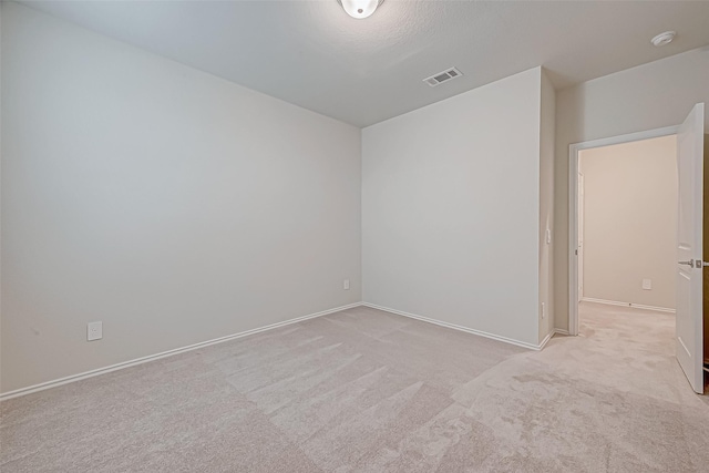 empty room with light carpet and a textured ceiling