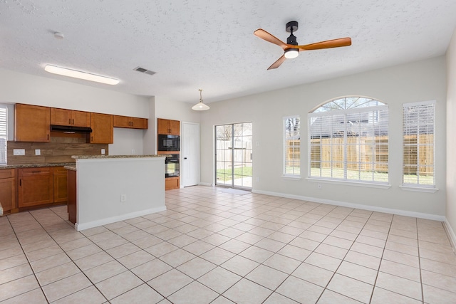 kitchen featuring a textured ceiling, light tile patterned floors, black microwave, and hanging light fixtures