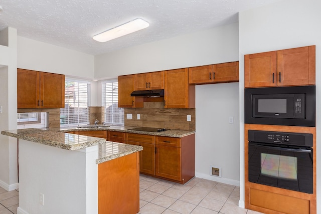 kitchen with light stone countertops, a textured ceiling, decorative backsplash, light tile patterned floors, and black appliances