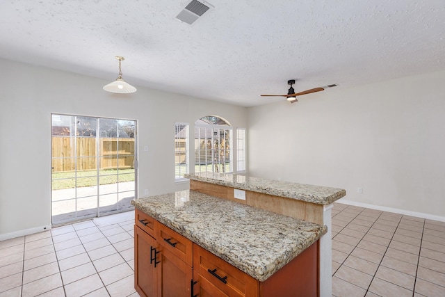 kitchen with a textured ceiling, a center island, decorative light fixtures, and light tile patterned floors