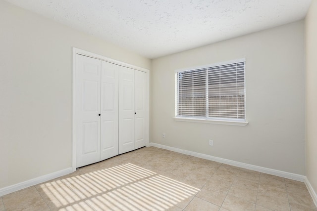 unfurnished bedroom featuring light tile patterned floors, a textured ceiling, and a closet