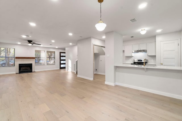 unfurnished living room with ceiling fan, light hardwood / wood-style floors, and a tile fireplace