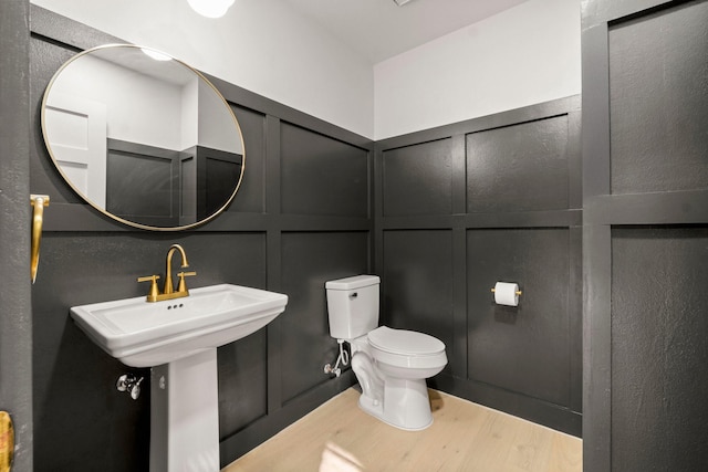 bathroom with toilet, wood-type flooring, and sink