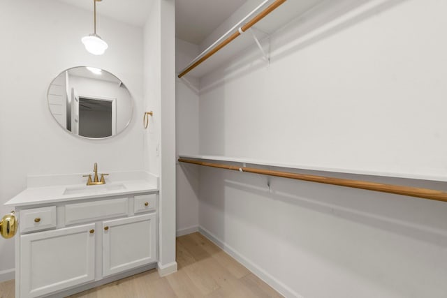 walk in closet with sink and light wood-type flooring