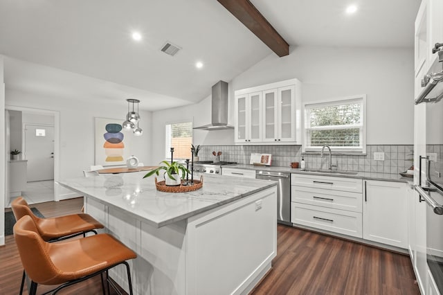 kitchen with white cabinetry, sink, a center island, wall chimney range hood, and appliances with stainless steel finishes