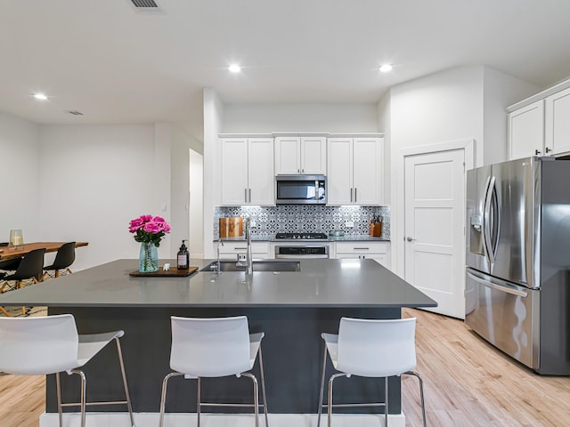 kitchen featuring a center island with sink, white cabinets, and stainless steel appliances