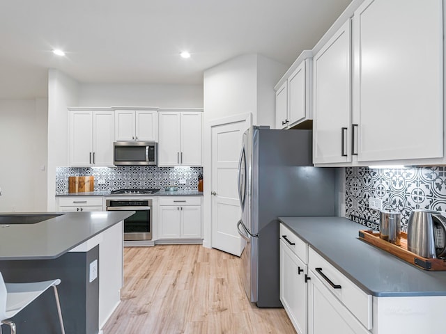 kitchen featuring decorative backsplash, stainless steel appliances, sink, light hardwood / wood-style flooring, and white cabinetry