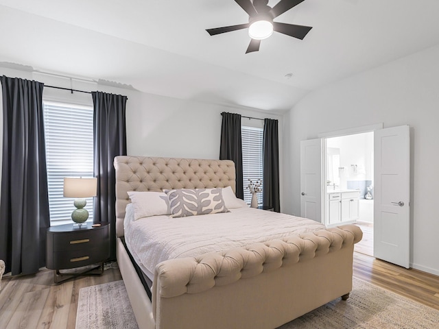 bedroom featuring light wood-type flooring, ensuite bath, vaulted ceiling, and ceiling fan