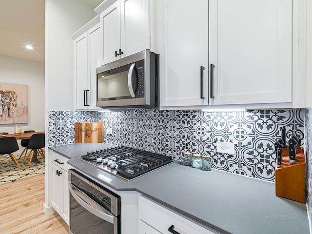 kitchen featuring white cabinets, decorative backsplash, stainless steel appliances, and light hardwood / wood-style floors