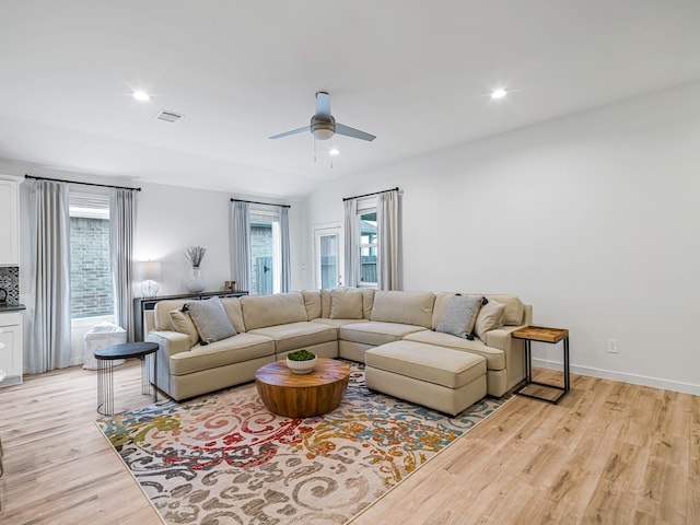 living room featuring ceiling fan, light hardwood / wood-style floors, and a wealth of natural light