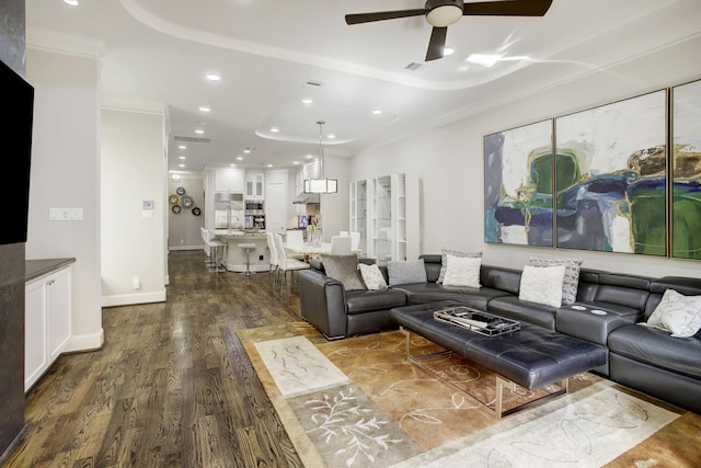 living room featuring ceiling fan, dark hardwood / wood-style floors, ornamental molding, and a tray ceiling