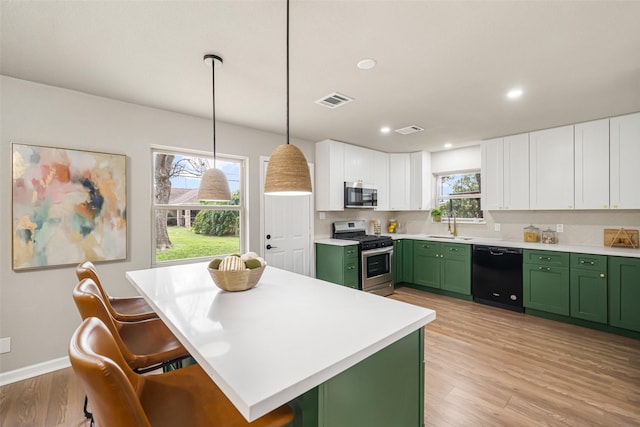 kitchen with sink, gas range, green cabinetry, hanging light fixtures, and dishwasher