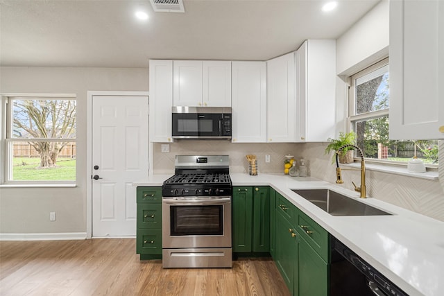 kitchen with sink, white cabinetry, green cabinetry, tasteful backsplash, and stainless steel appliances