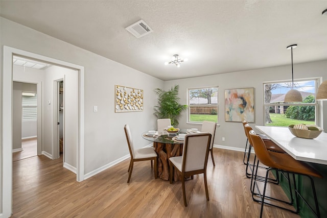 dining area with a textured ceiling and light hardwood / wood-style floors