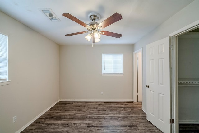 empty room featuring ceiling fan, a wealth of natural light, and dark hardwood / wood-style floors