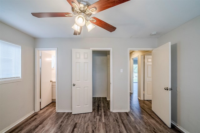 unfurnished bedroom with ceiling fan, ensuite bath, dark wood-type flooring, and a walk in closet