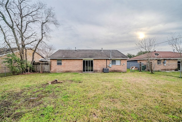 rear view of house featuring central AC unit and a yard