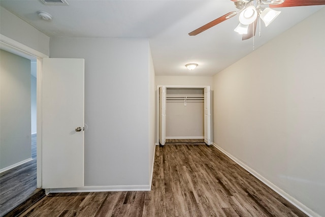 unfurnished bedroom featuring dark wood-type flooring, ceiling fan, and a closet