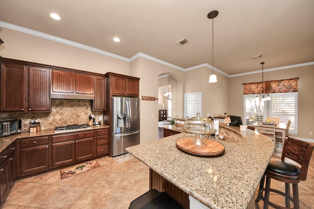 kitchen featuring hanging light fixtures, ornamental molding, appliances with stainless steel finishes, and a breakfast bar area