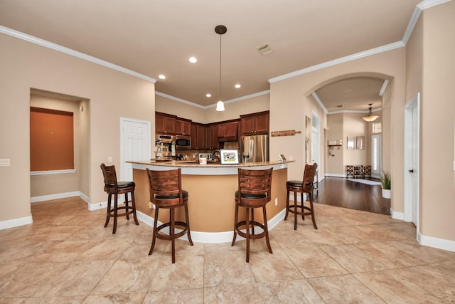 kitchen with decorative light fixtures, stainless steel appliances, kitchen peninsula, and a kitchen bar