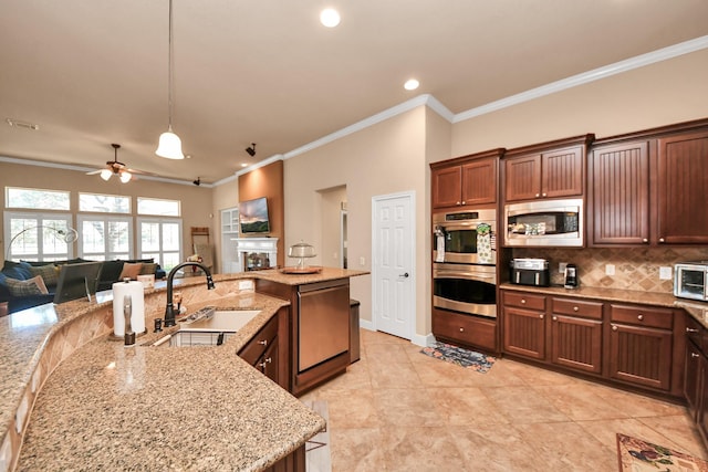 kitchen with sink, appliances with stainless steel finishes, hanging light fixtures, light stone countertops, and decorative backsplash