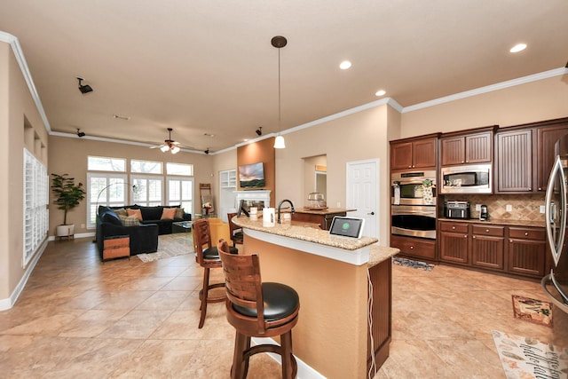 kitchen featuring a breakfast bar area, ceiling fan, stainless steel appliances, light stone counters, and decorative light fixtures