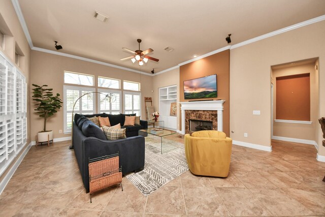 living room featuring light tile patterned floors, a fireplace, ornamental molding, and ceiling fan