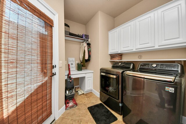 laundry area featuring light tile patterned floors, washer and clothes dryer, and cabinets