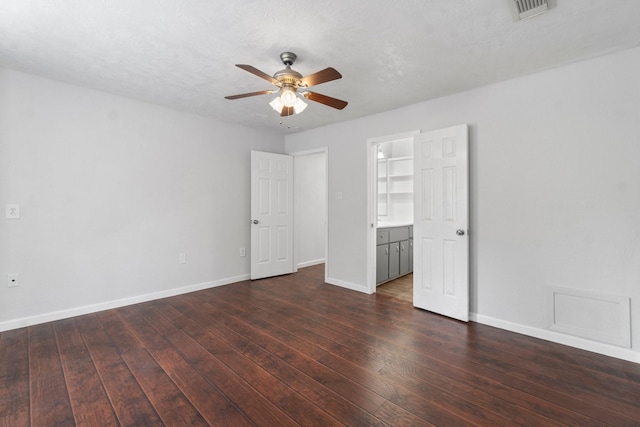 unfurnished bedroom featuring a textured ceiling, ceiling fan, dark wood-type flooring, a spacious closet, and a closet