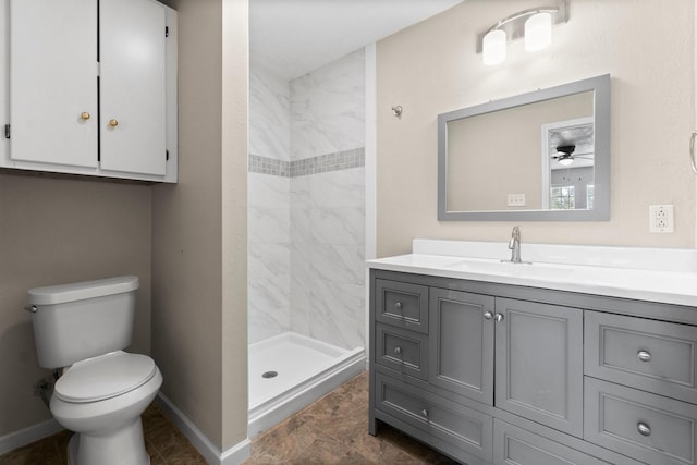 bathroom with vanity, ceiling fan, toilet, and tiled shower