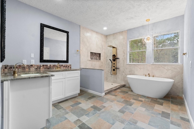 bathroom with vanity, a textured ceiling, an inviting chandelier, tile walls, and shower with separate bathtub