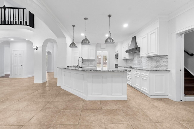 kitchen featuring white cabinets, backsplash, a kitchen island with sink, and custom exhaust hood