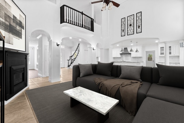 living room with tile patterned flooring, a towering ceiling, ceiling fan, and sink