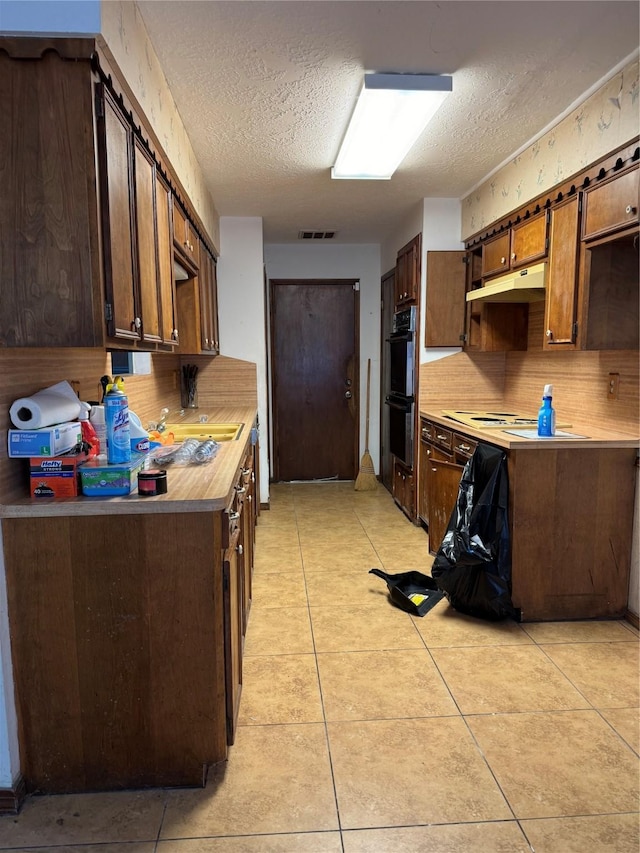 kitchen with light tile patterned floors, a textured ceiling, dark brown cabinets, and double oven