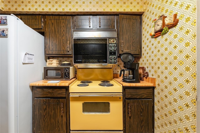 kitchen featuring dark brown cabinetry and white appliances